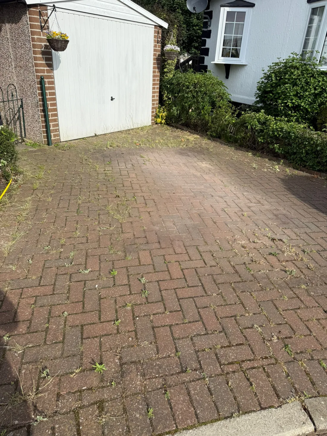 Weathered block paving with weeds before cleaning