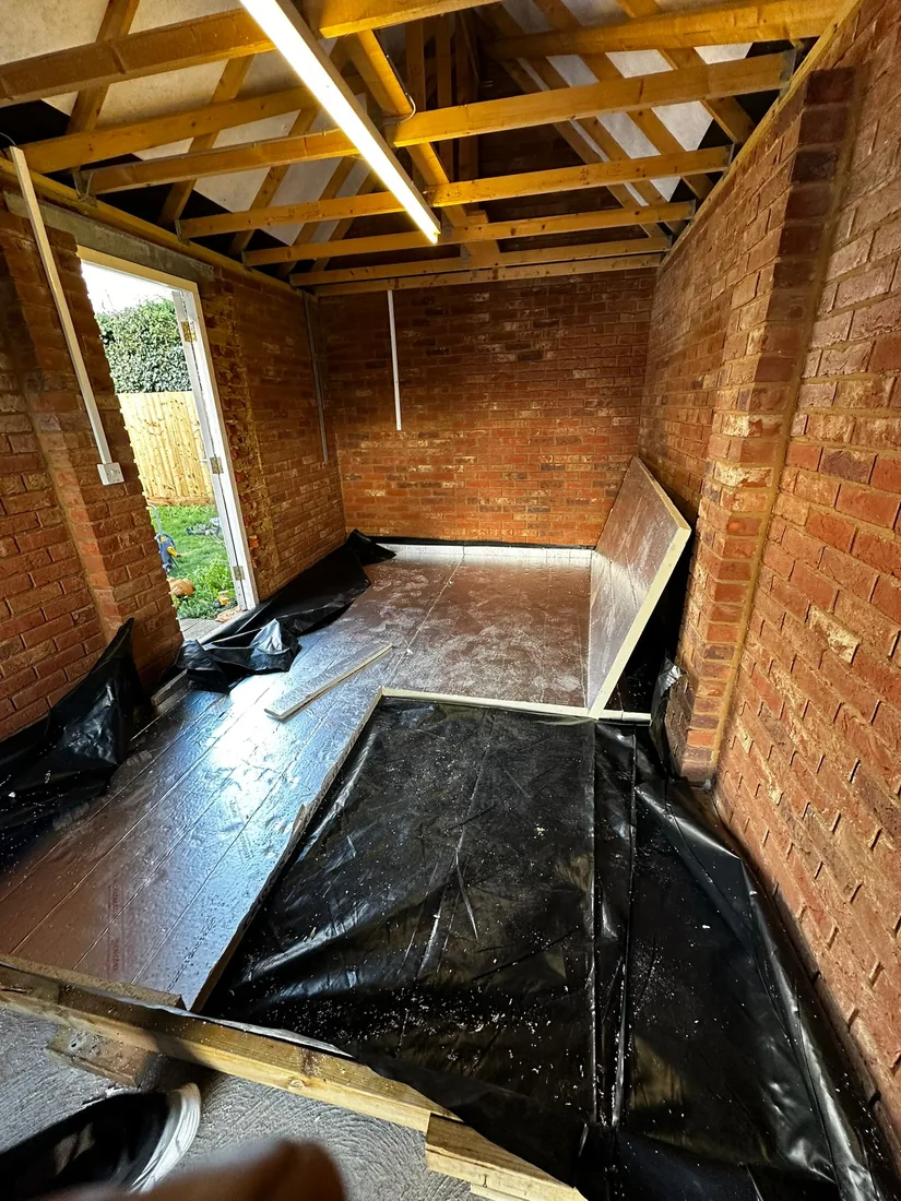 Floor membrane and insulation being installed in an empty bare-brick garage near Elmswell